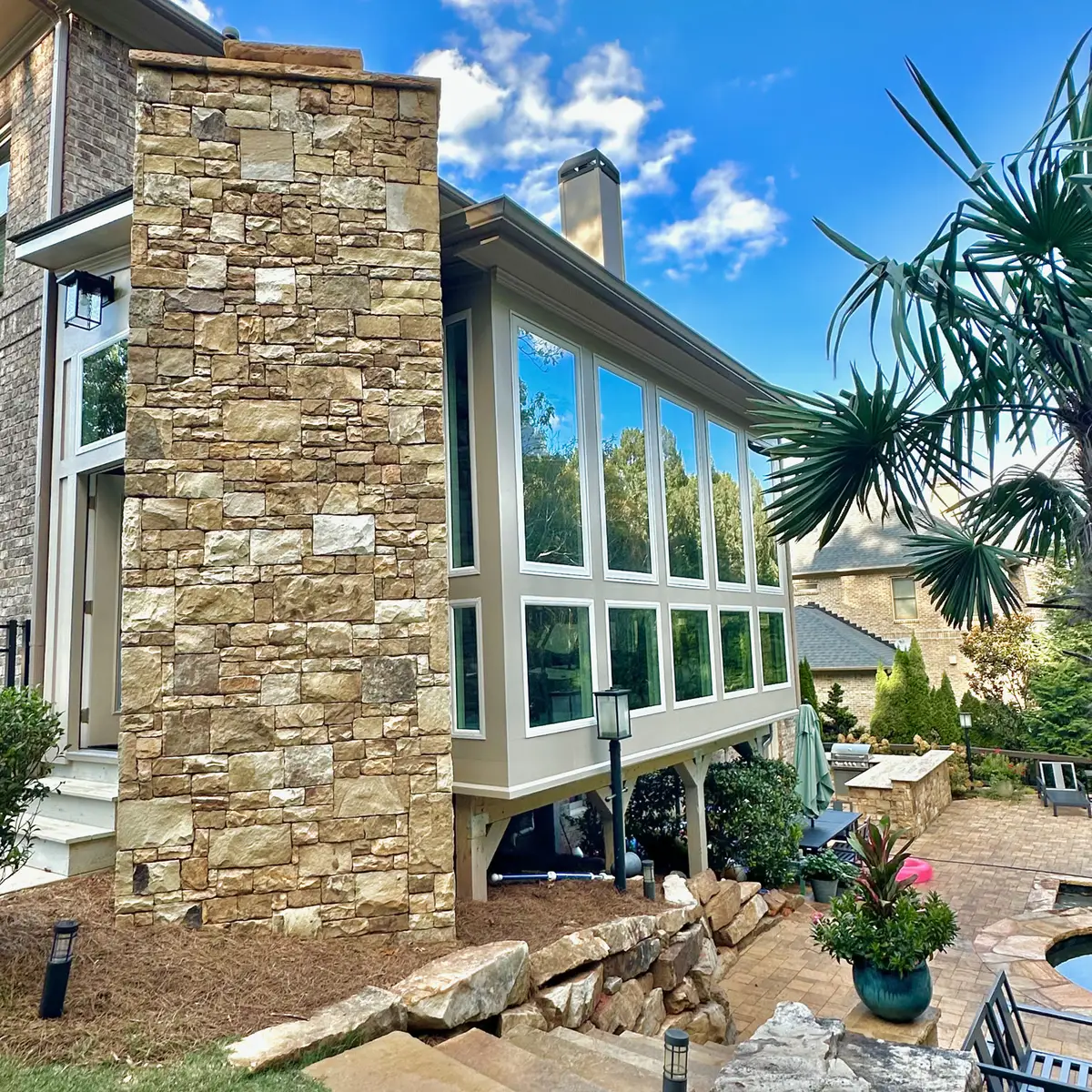 Sunroom with stone chimney and tall windows