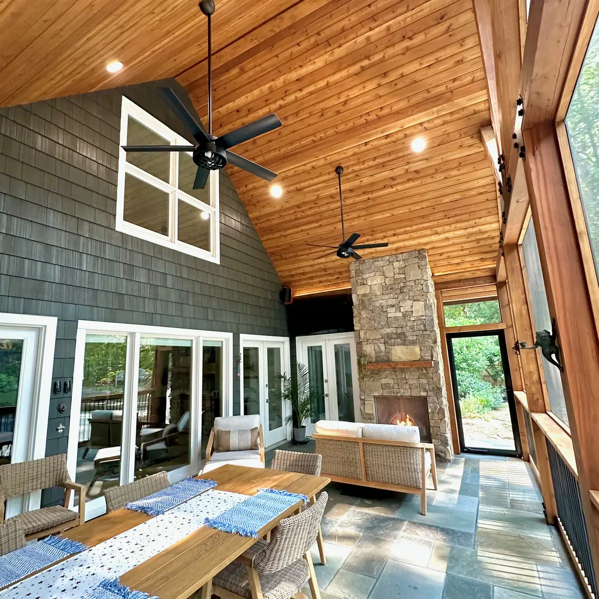Vaulted screened porch with stone fireplace and dining table
