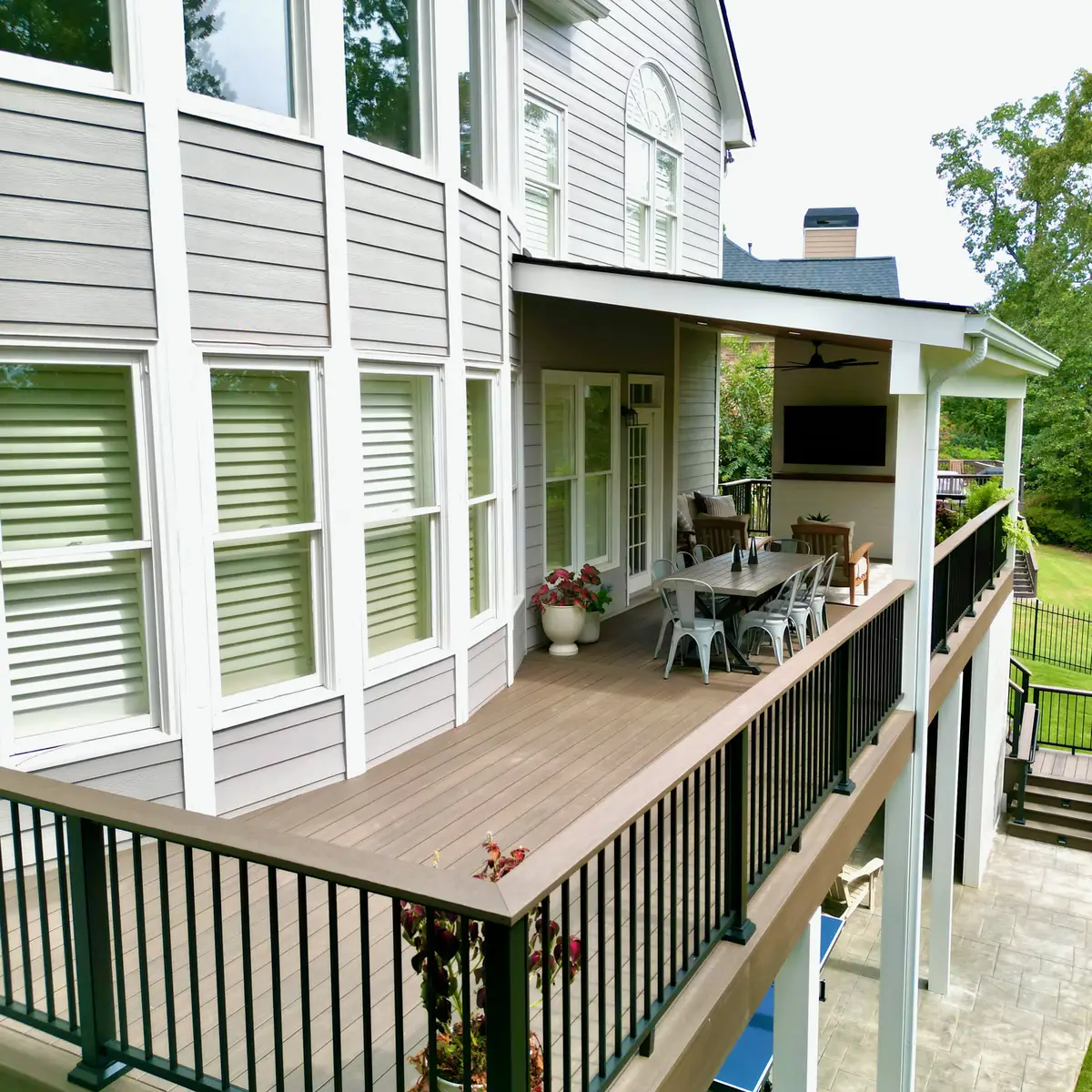 Covered composite deck with outdoor dining, TV and black aluminum railings