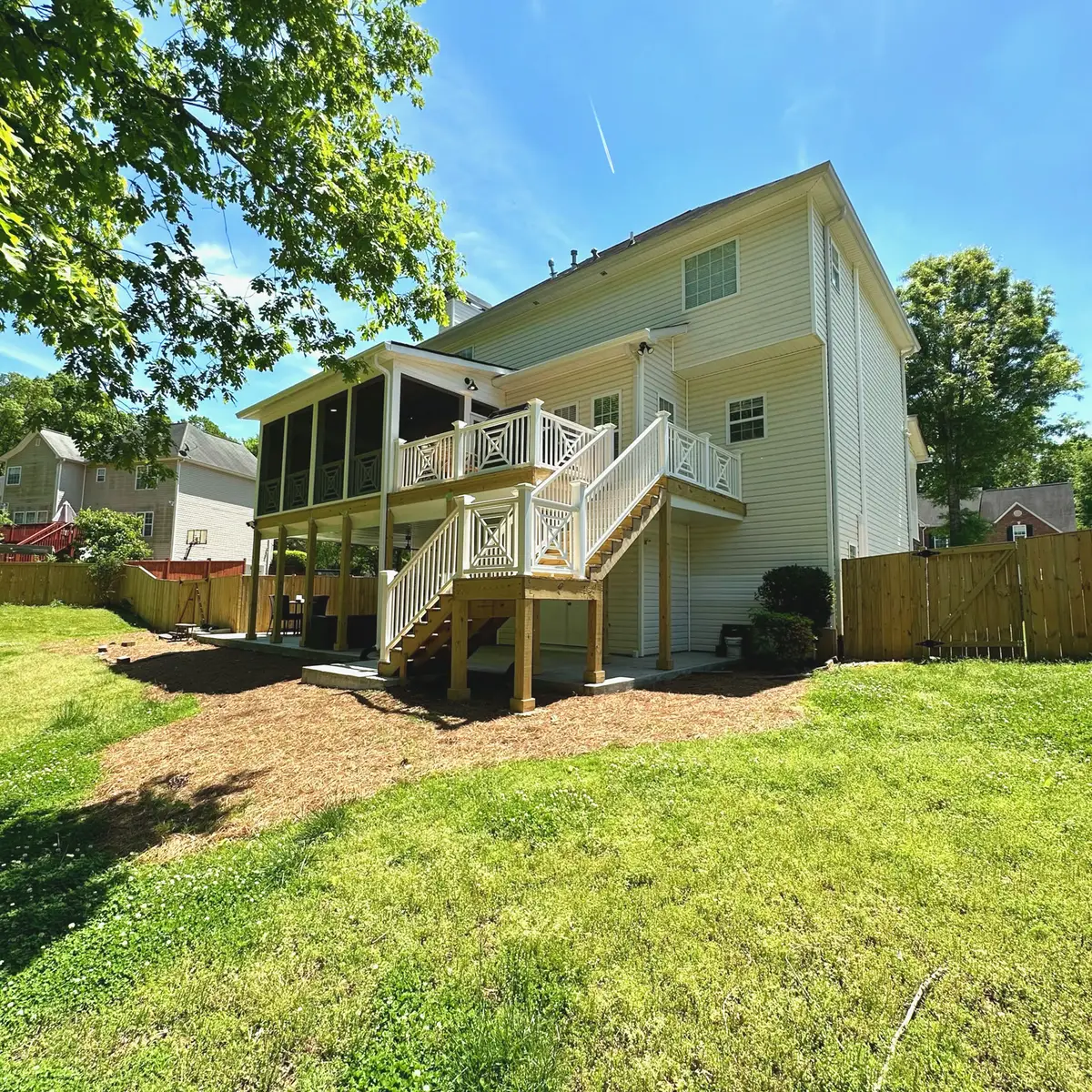 Screened porch over a covered patio with white stairs on a two-story home