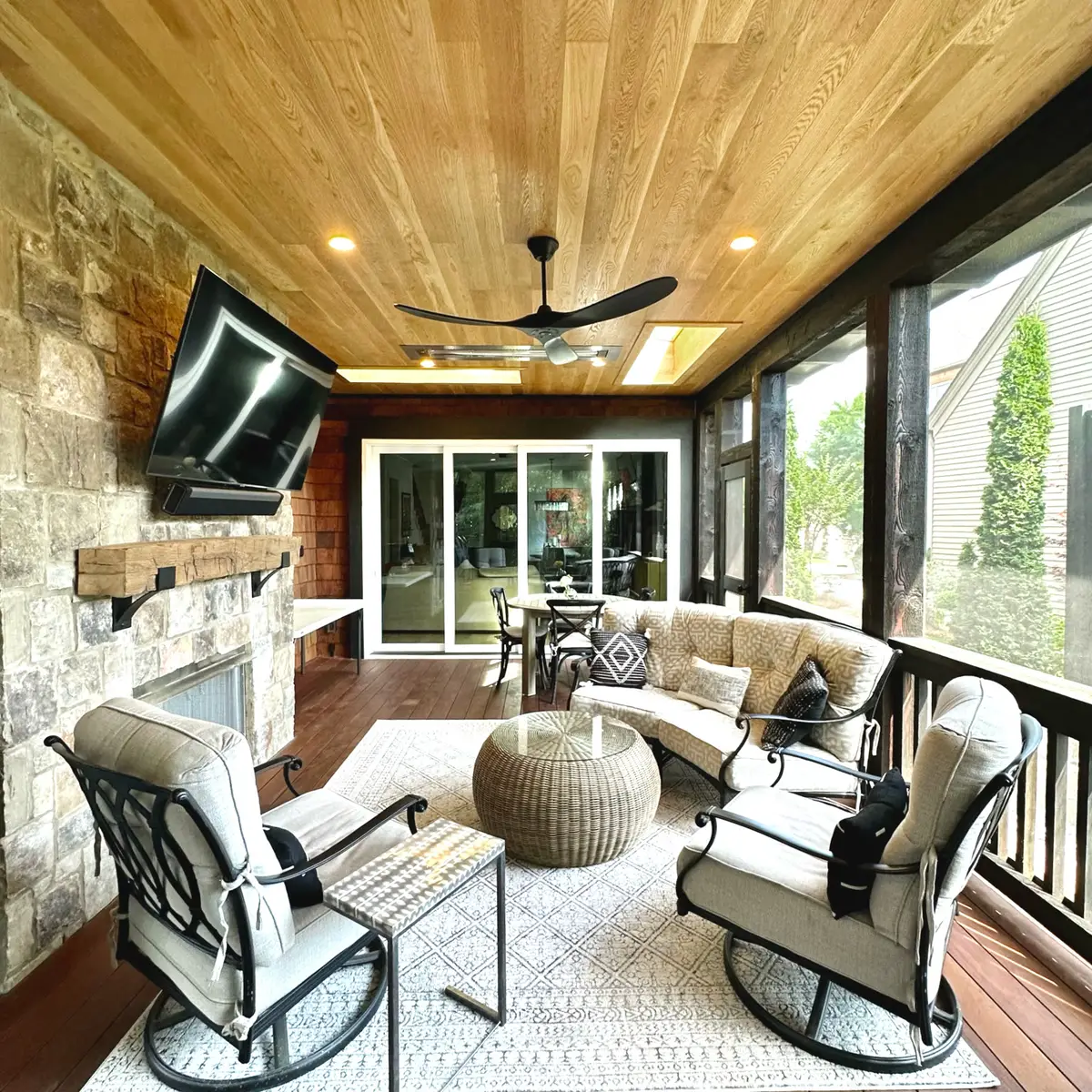 Screened porch lounge with TV, fireplace and wood ceiling