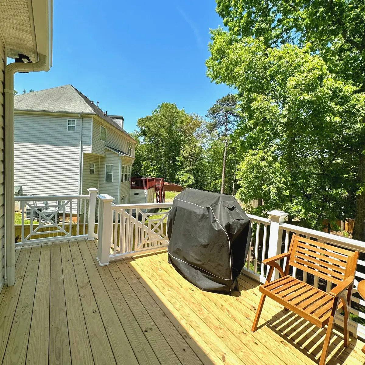 New pressure-treated deck with white railings and a grill area