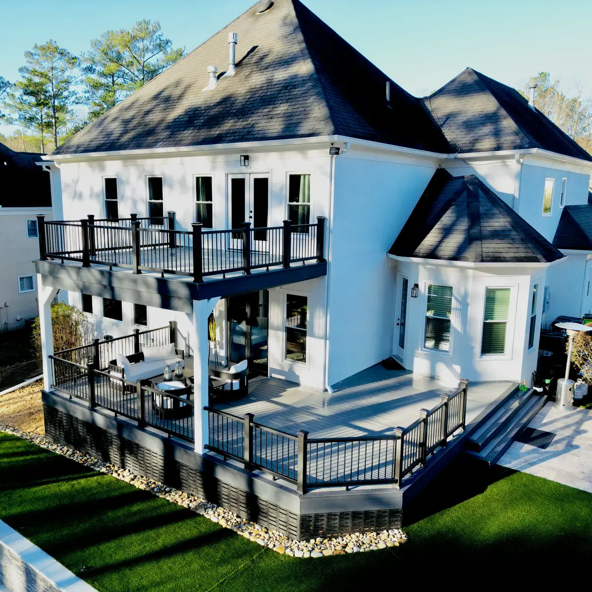 Aerial view of a two-level deck with upper balcony and lower entertaining deck beside turf lawn