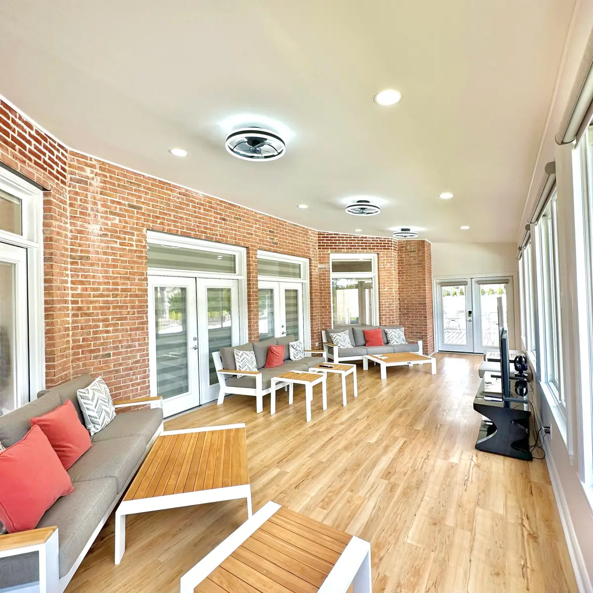 Sunroom interior with exposed brick, French doors and modern ceiling fans