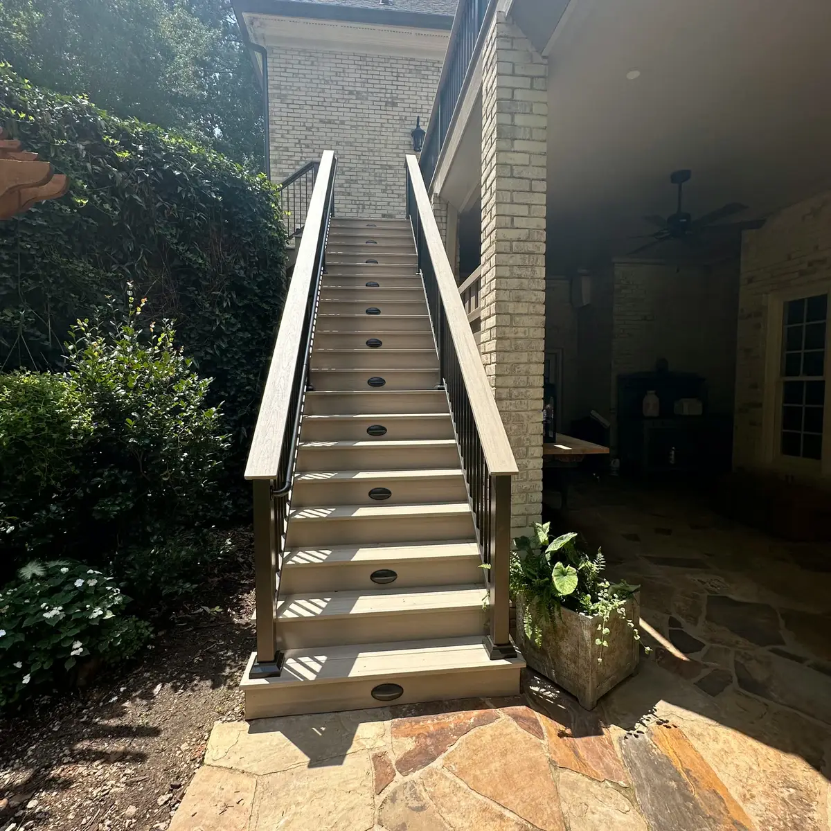 Deck stairs with dark railings above a flagstone patio