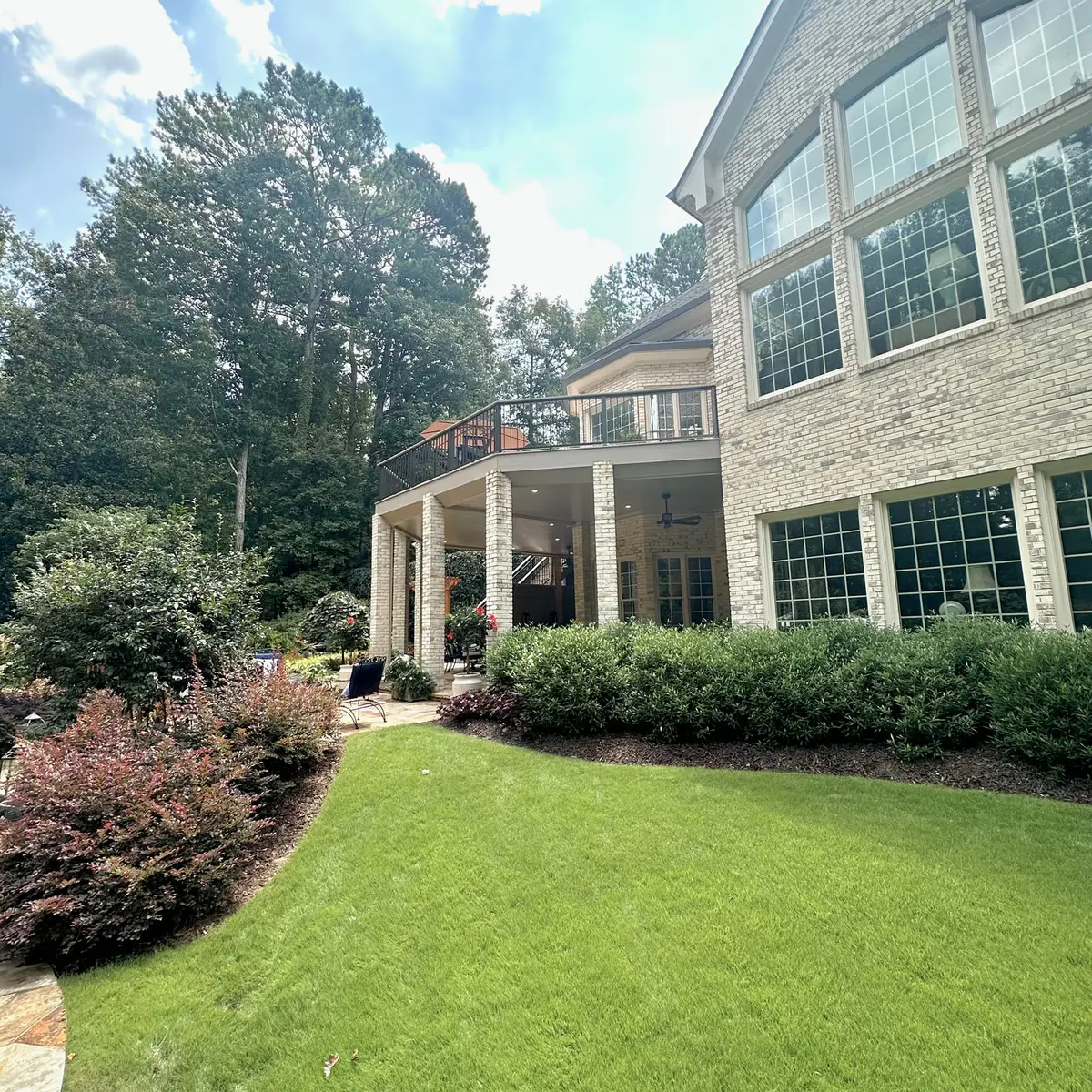 Elevated deck on a large stone home with landscaped lawn