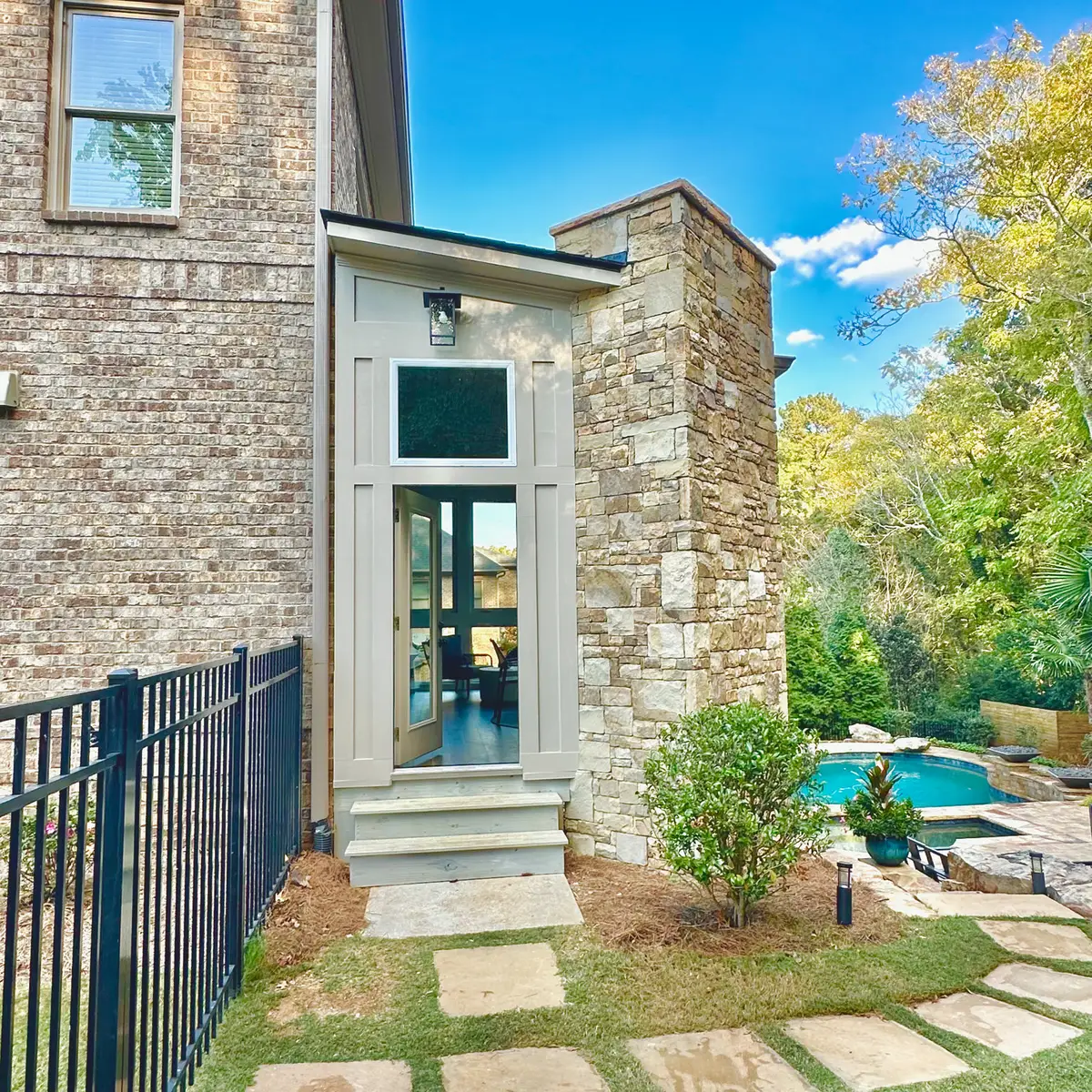 Sunroom entry with stone chimney beside a pool
