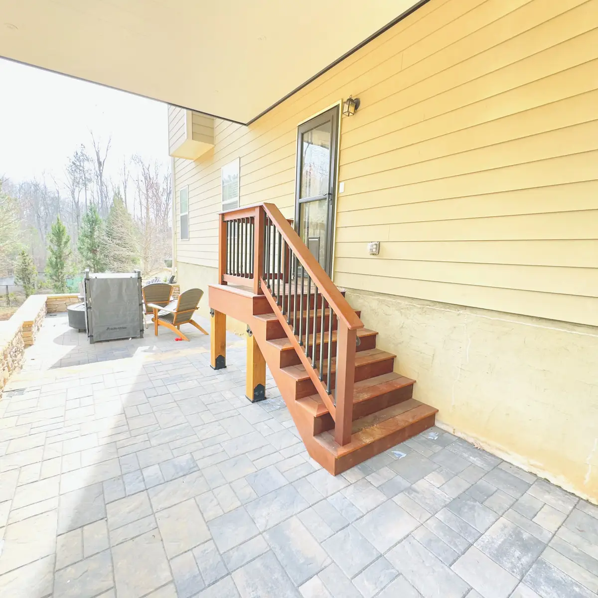 Wood deck stairs with cedar railings to a paver patio