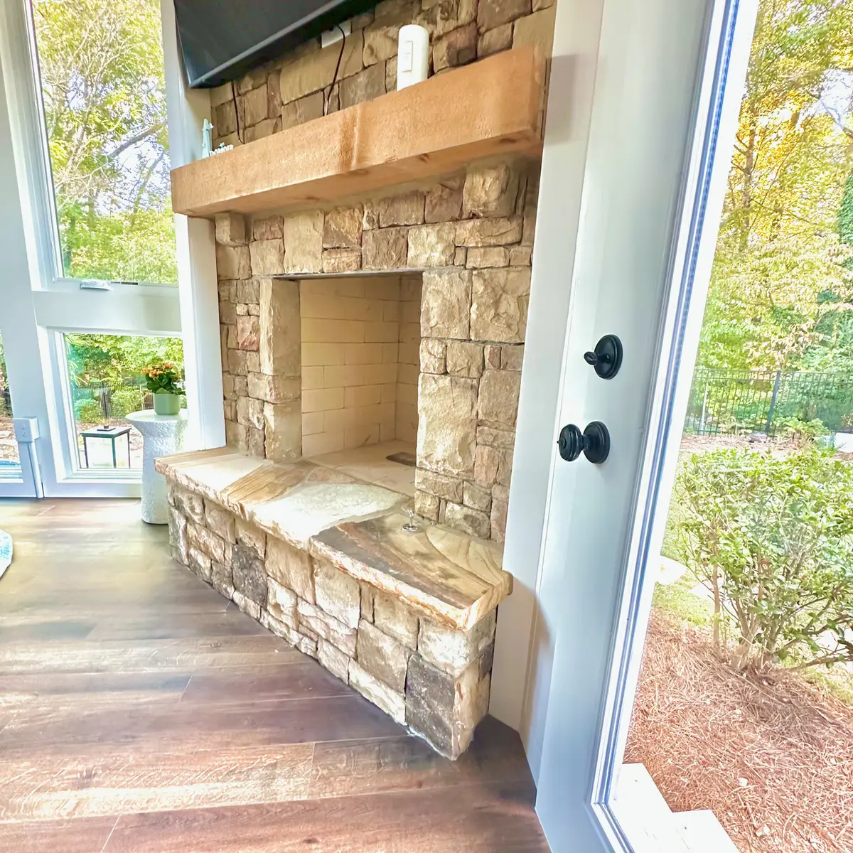Stacked stone fireplace with hearth in a sunroom