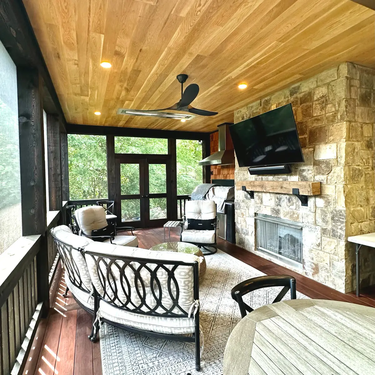 Screened porch with black framing, cedar ceiling and stone fireplace