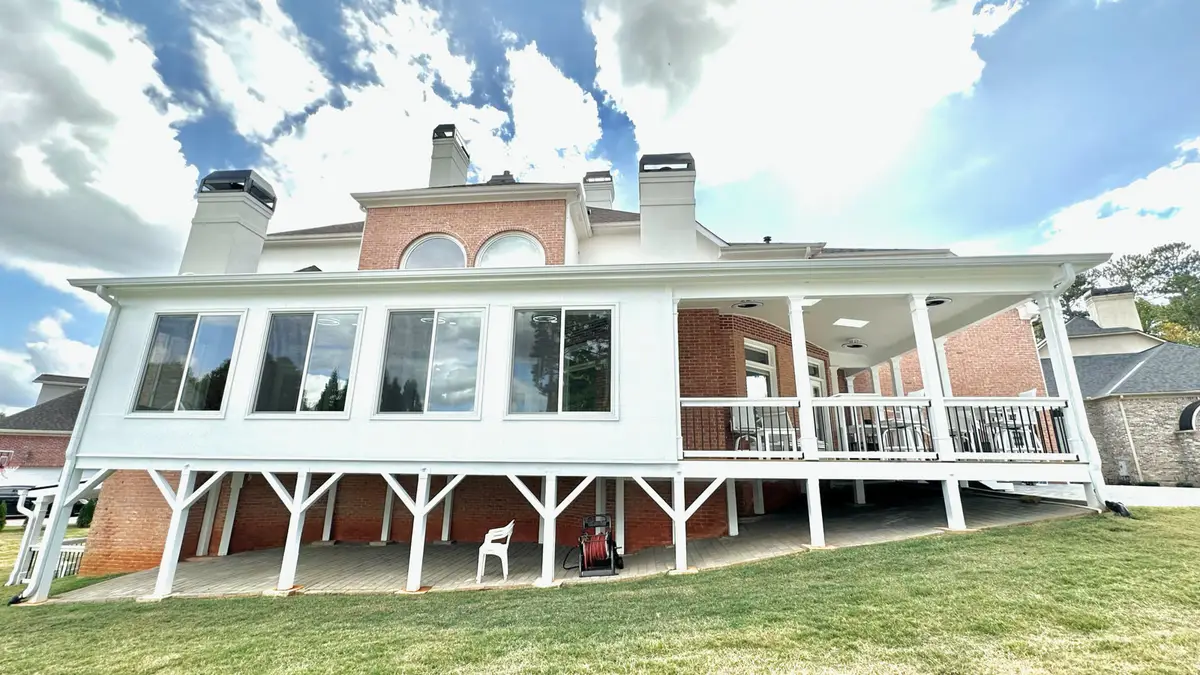 Sunroom and covered porch addition with white railings on a brick home