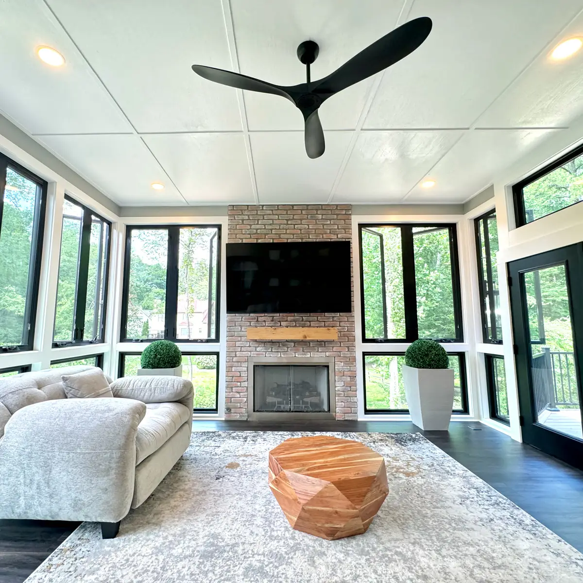 Sunroom with brick fireplace and wall of black-framed windows