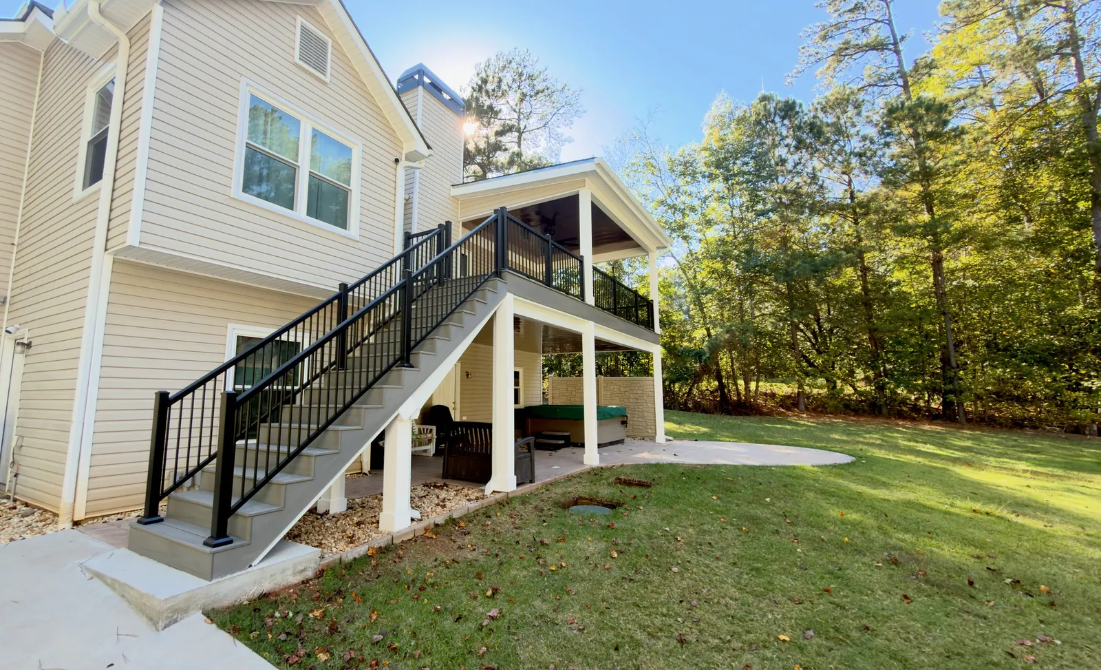 Composite stairs with black aluminum rail climbing to the covered deck