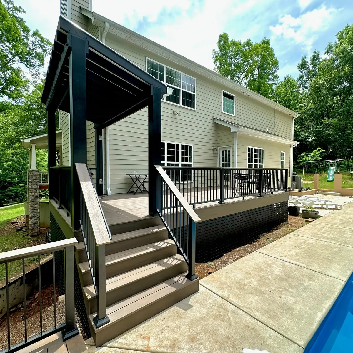 Composite pool deck with black railings and a black metal pergola