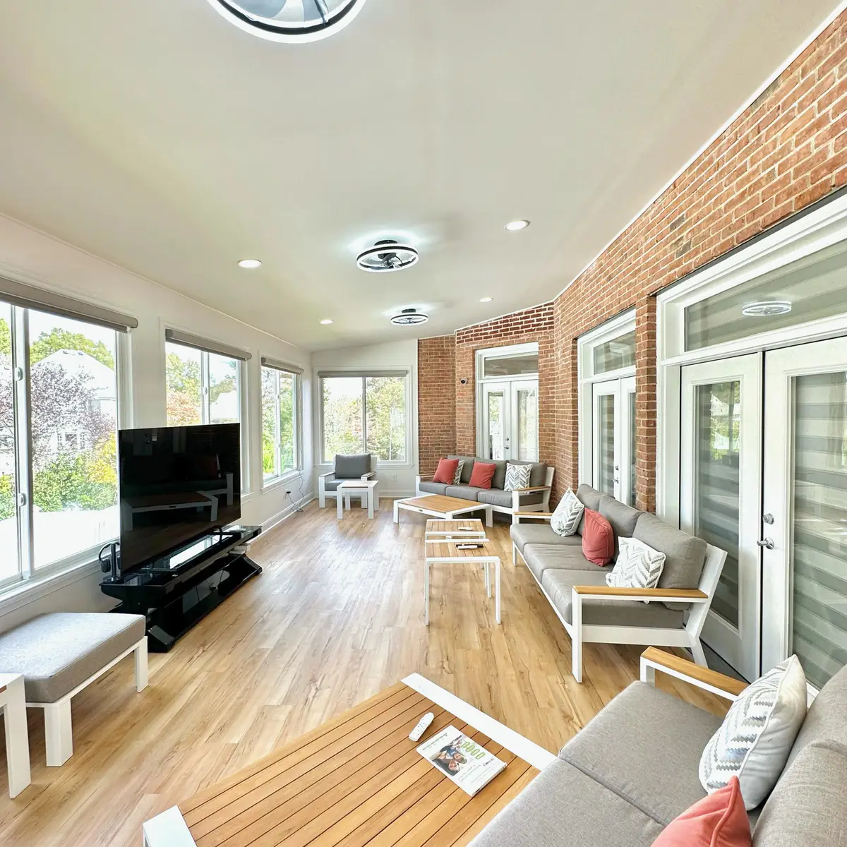 Spacious sunroom with brick accent wall, TV and lounge furniture