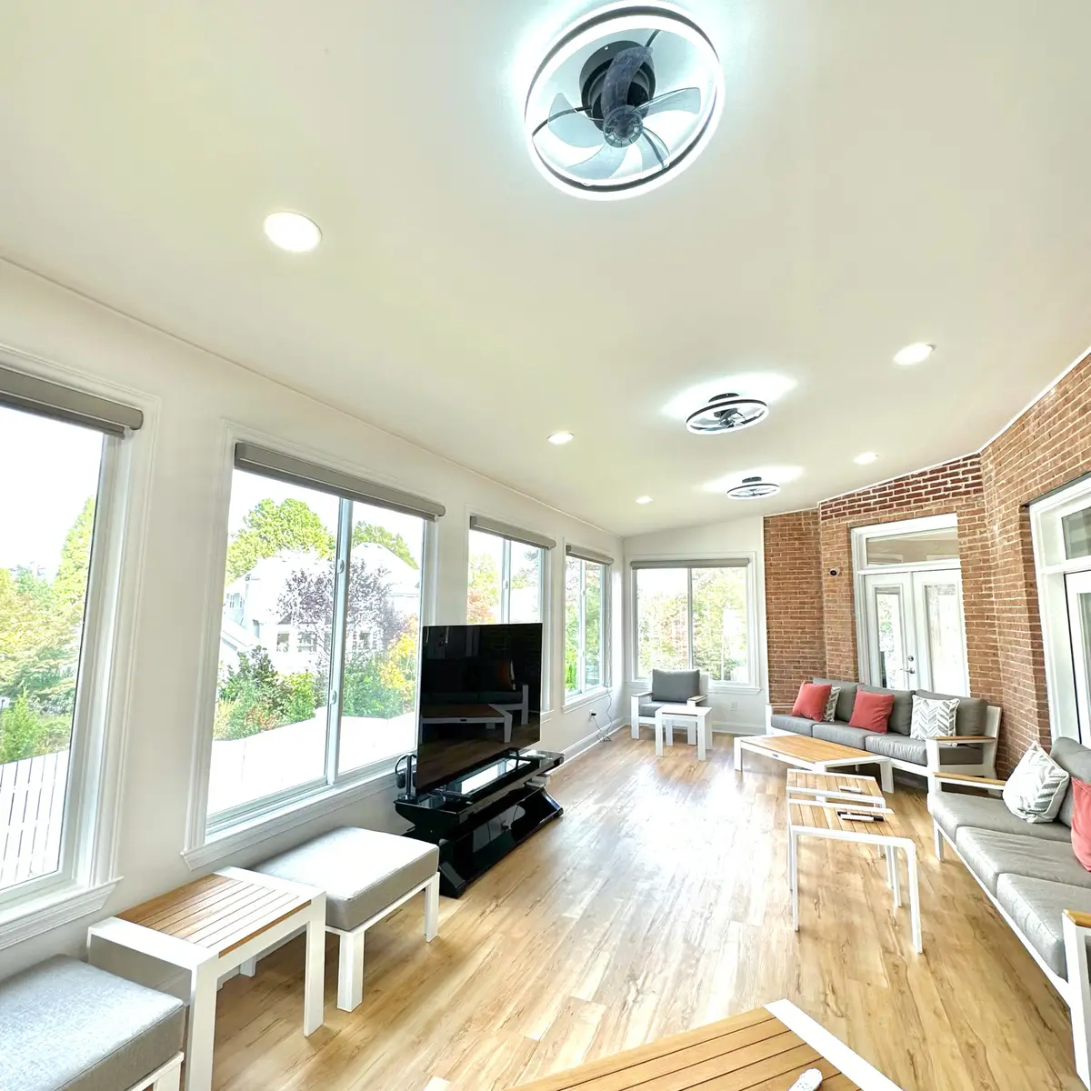 Sunroom with wall of windows, brick wall and wood-look floors