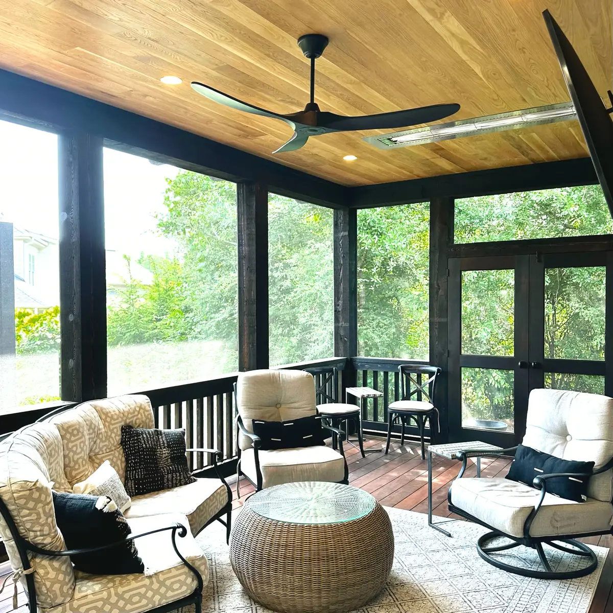 Screened porch seating area with dark frame and wooded view