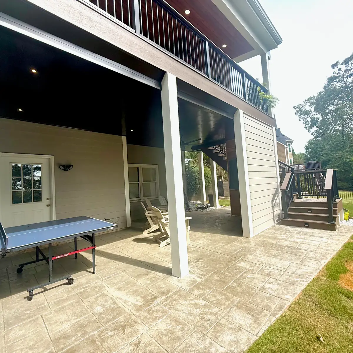 Smyrna stamped concrete patio with white support columns and stairs to the upper deck