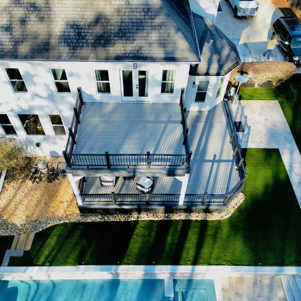 Overhead view of a grey composite deck with black railings above a backyard pool