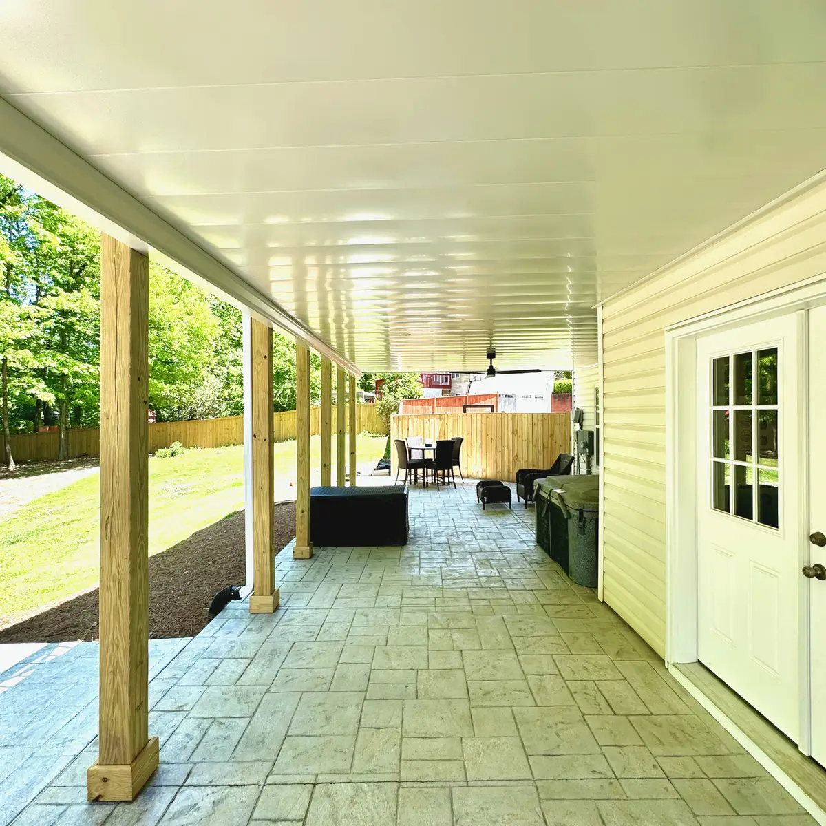 Covered stamped-concrete patio beneath a deck with wood posts