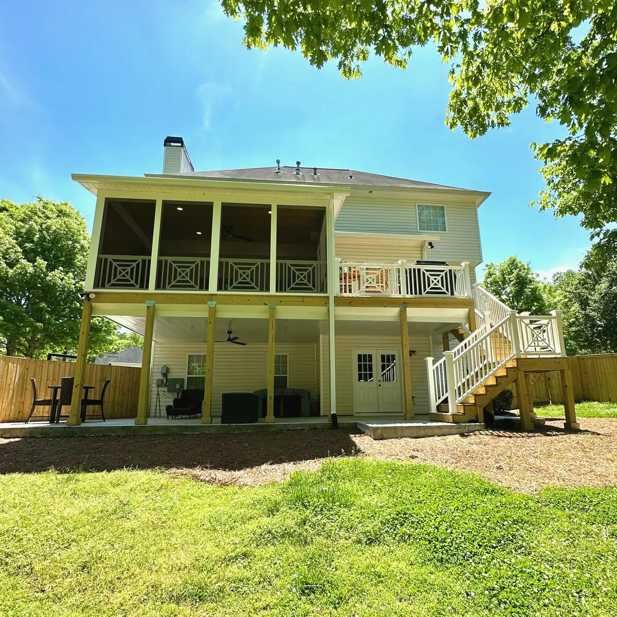 Two-story screened porch with lattice railings and stairs to the yard