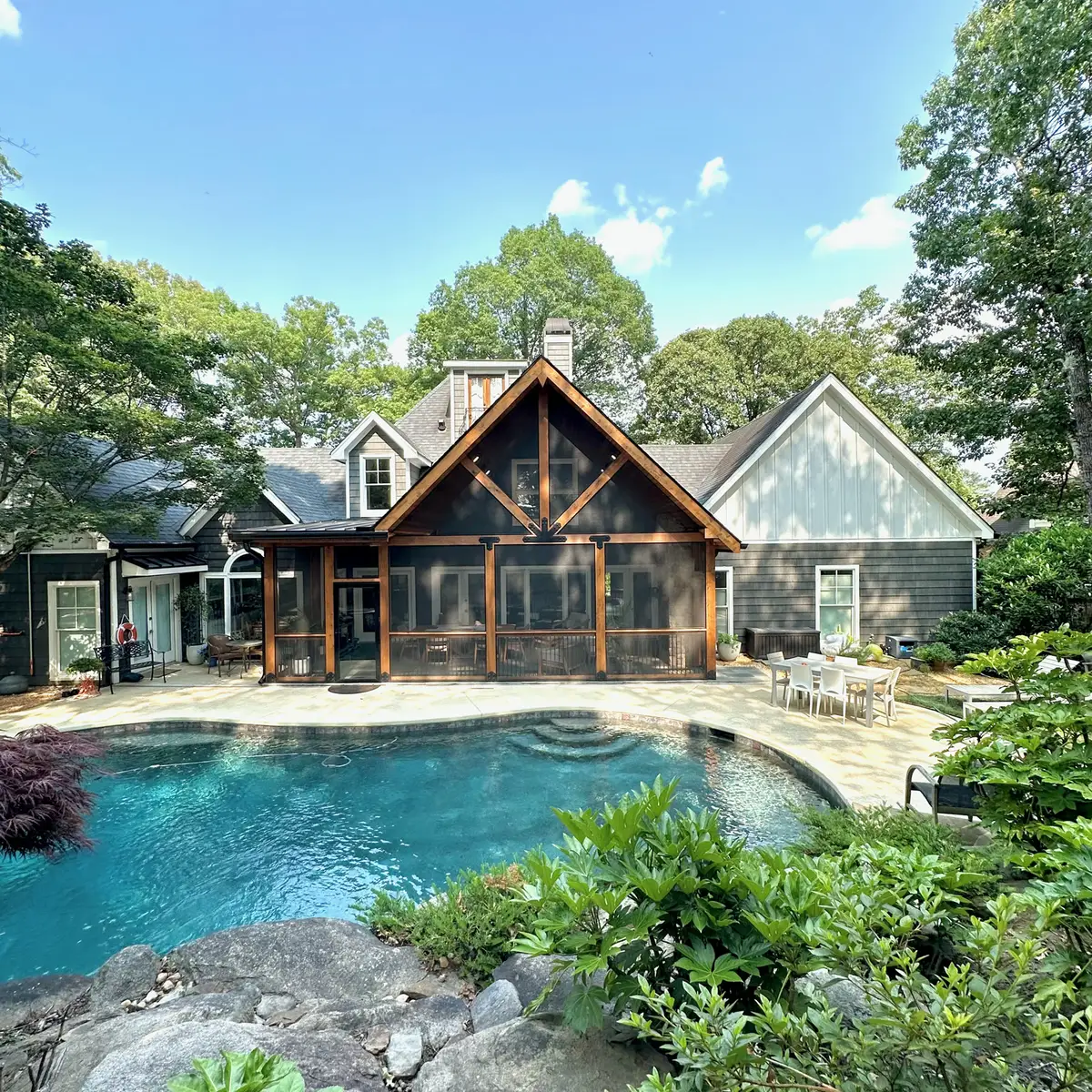 Timber gable screened porch behind a pool and gardens