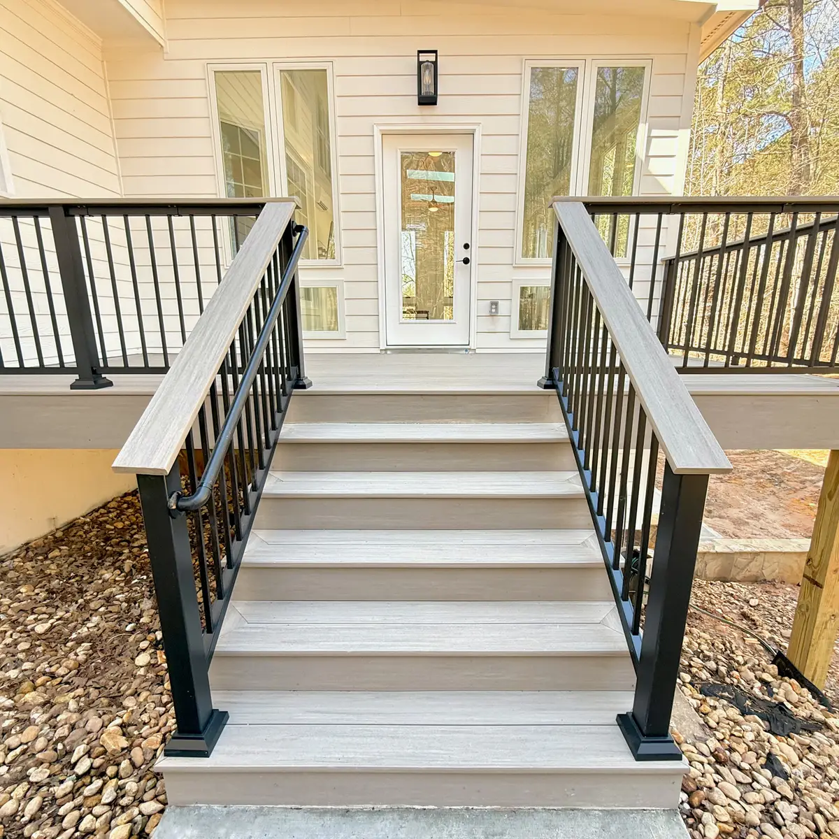 Composite deck stairs with black railings to a back door