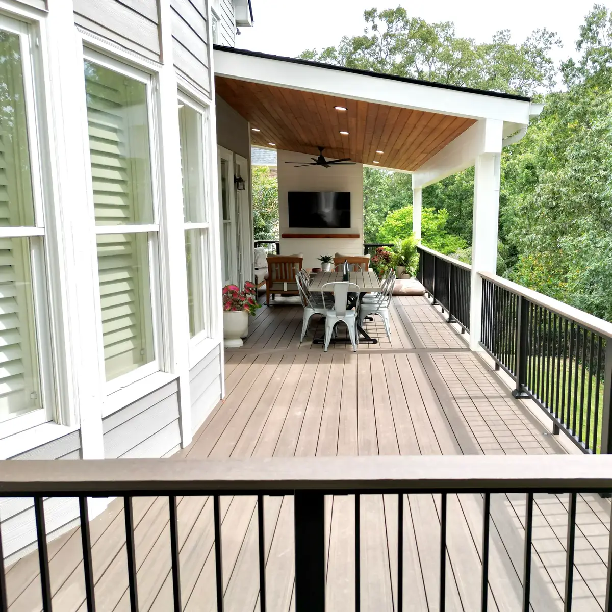 Smyrna covered deck dining space with cedar ceiling, recessed lights, ceiling fan and black drink rail