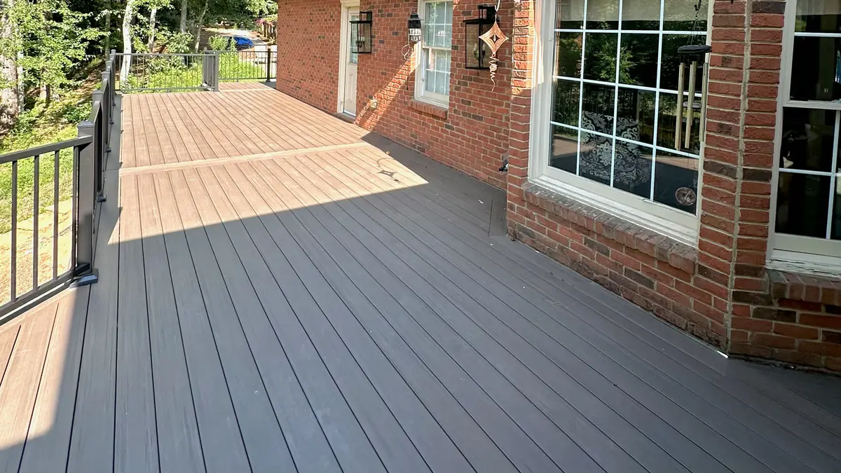 Composite deck with black railings along a brick home