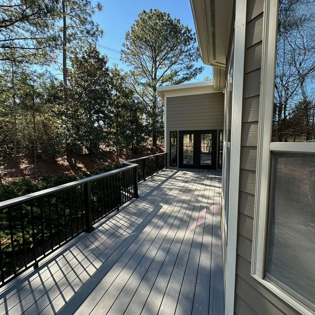 Composite deck with black railings facing pine trees