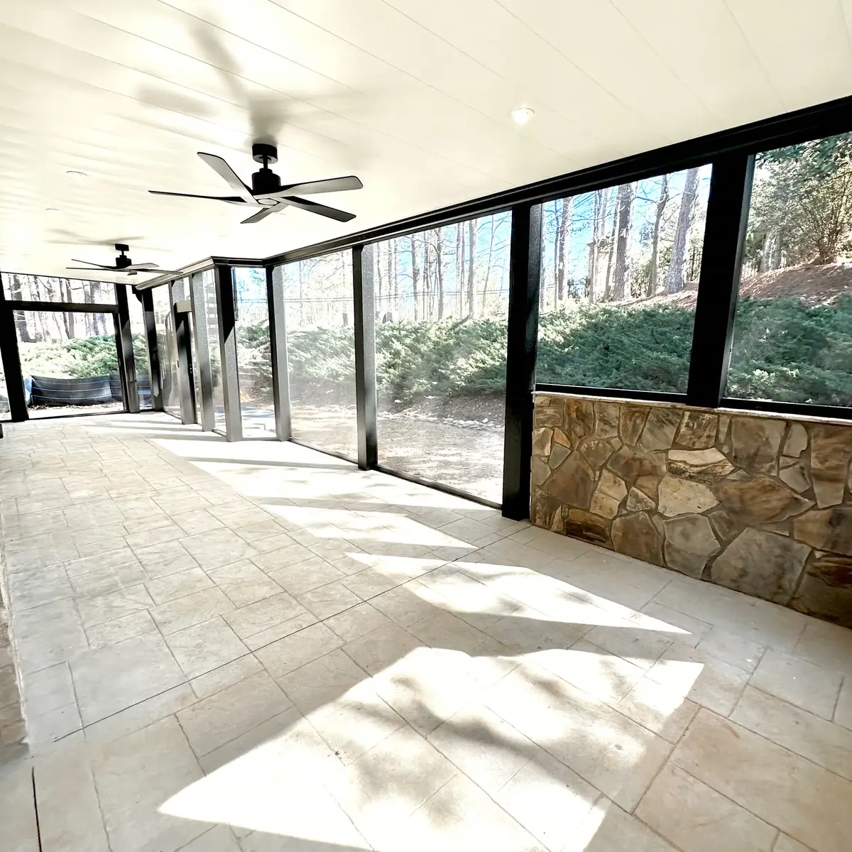 Screened patio with stone knee wall and ceiling fans