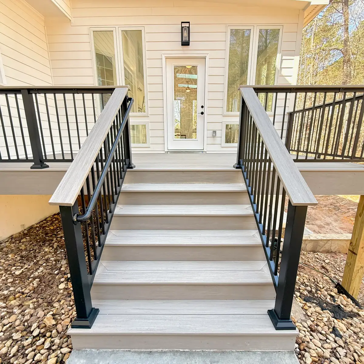 Fayetteville deck stairs with cocktail rail and black aluminum balusters leading to the concrete walkway