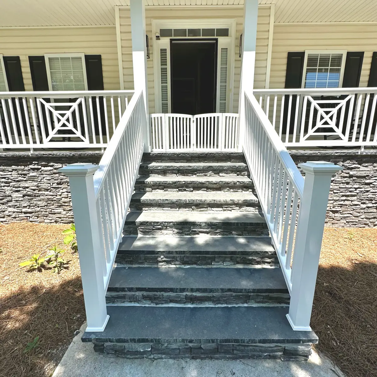 Front porch stairs with white railings and slate-colored treads