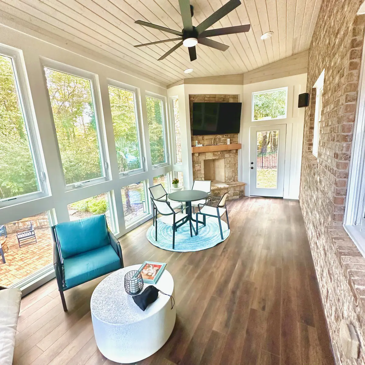 Bright sunroom with stone fireplace, pine ceiling and lounge seating
