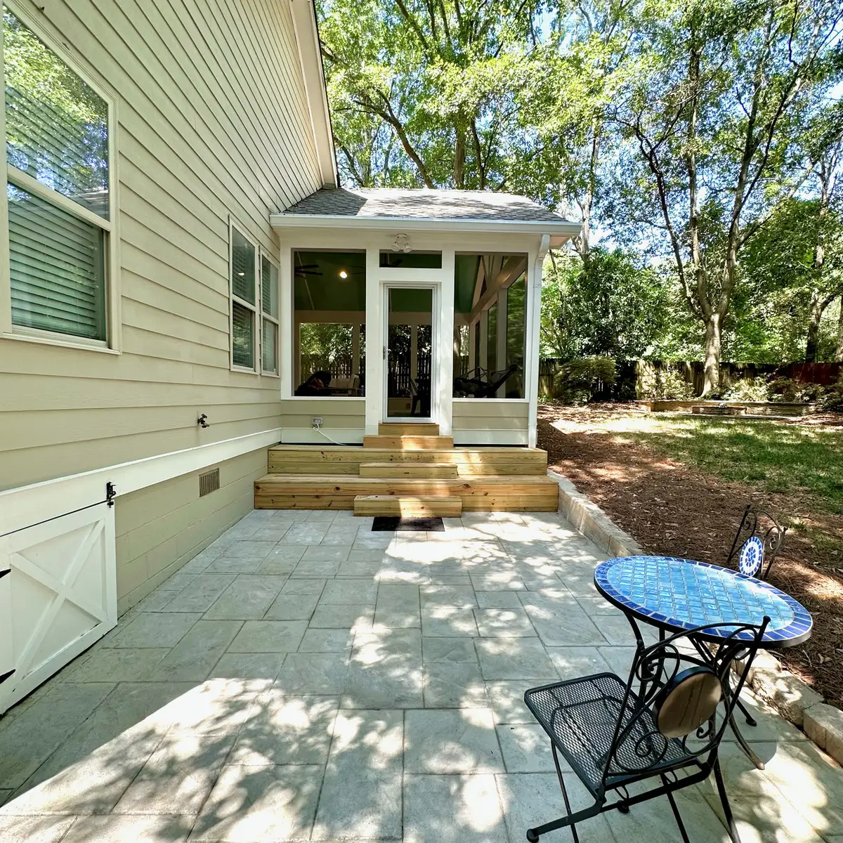 Screened porch entry with steps down to a stamped-concrete patio