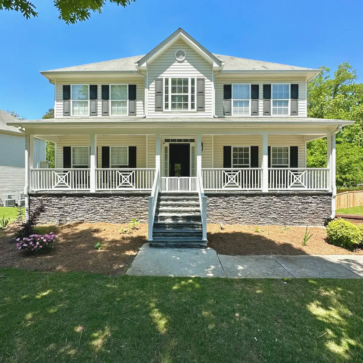 Front porch with white railings and stone-faced steps on a colonial home