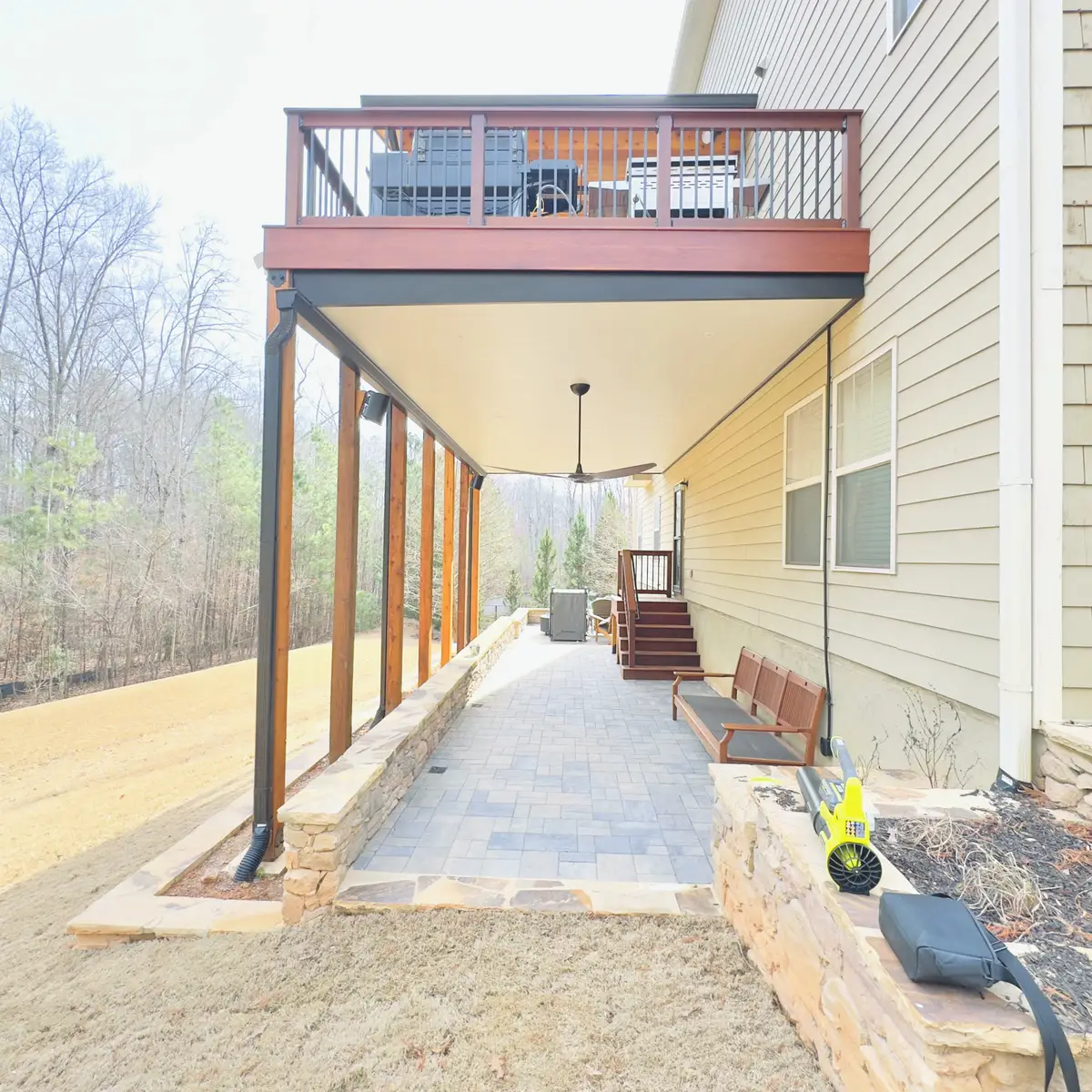 Covered patio under an upper deck with wood posts
