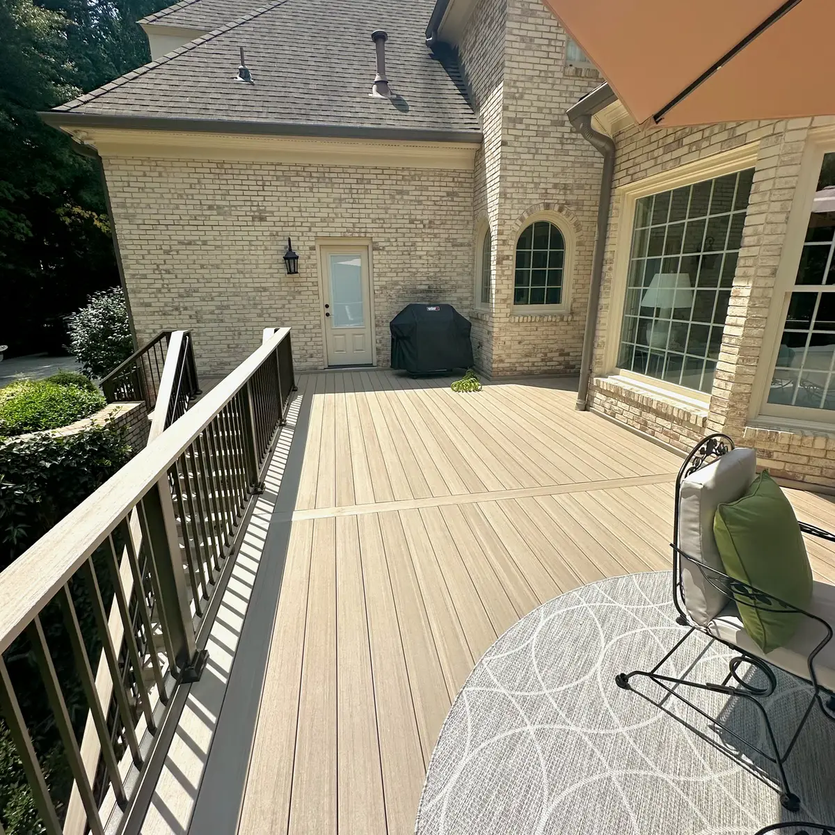 Composite deck with black railings along a stone home