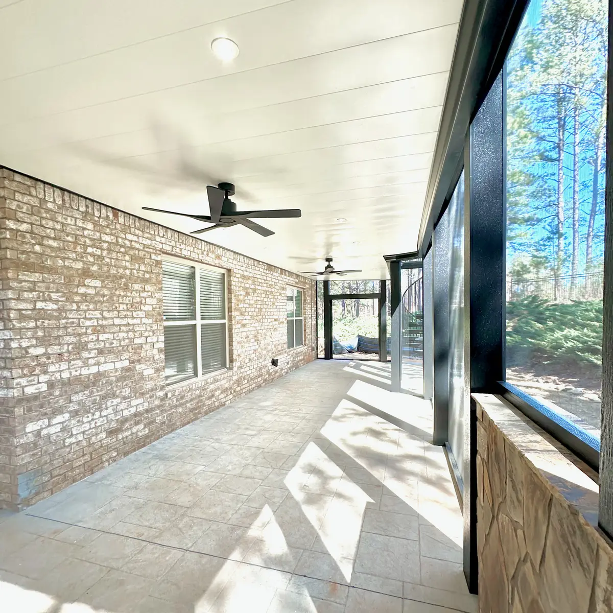 Screened patio with brick wall and ceiling fans
