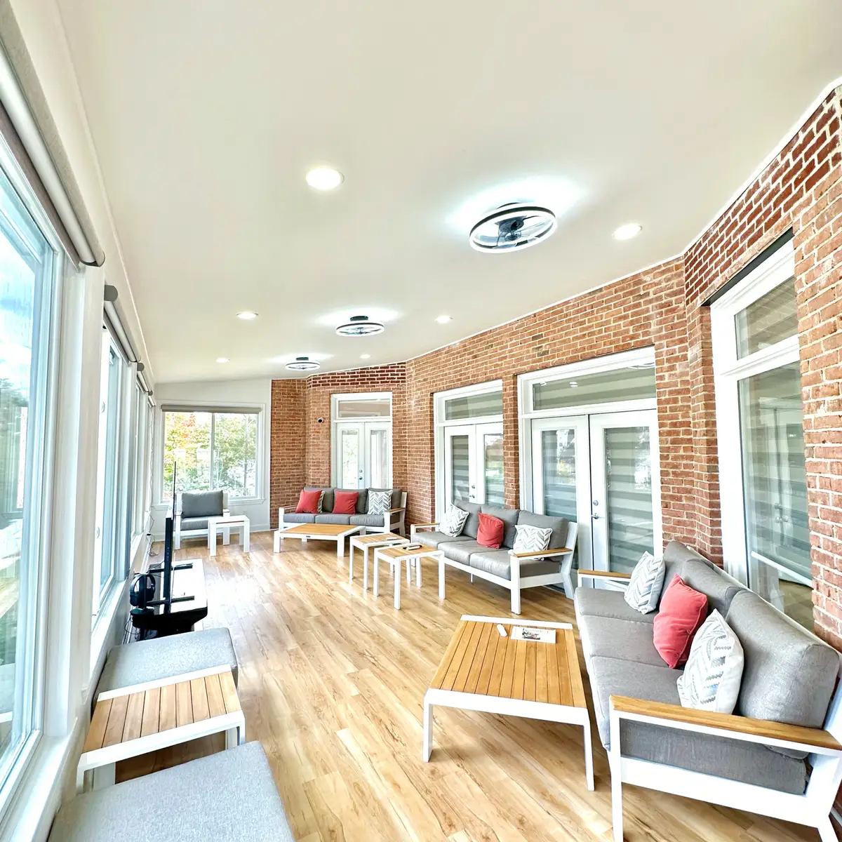 Sunroom living area with brick wall, French doors and ceiling fans