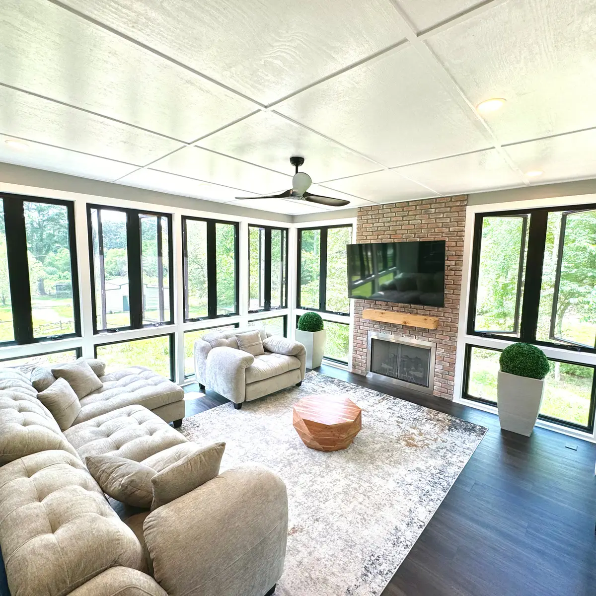 Sunroom with brick fireplace, black window frames and TV