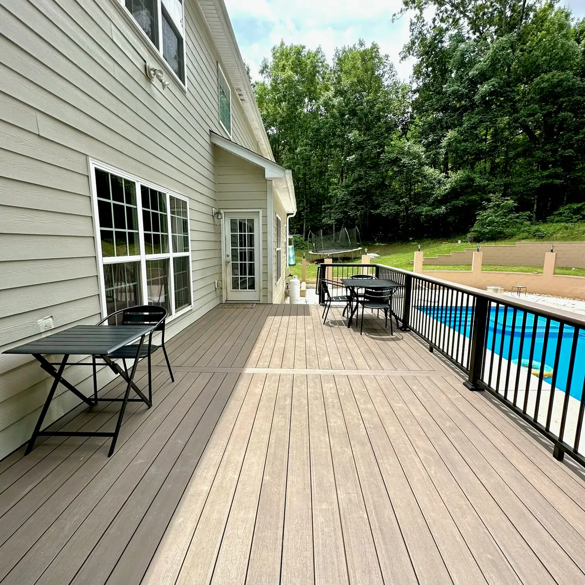 Long composite deck with black aluminum railings overlooking a pool