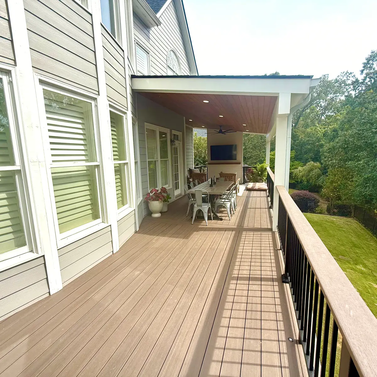 Long covered composite deck with black railings and outdoor dining