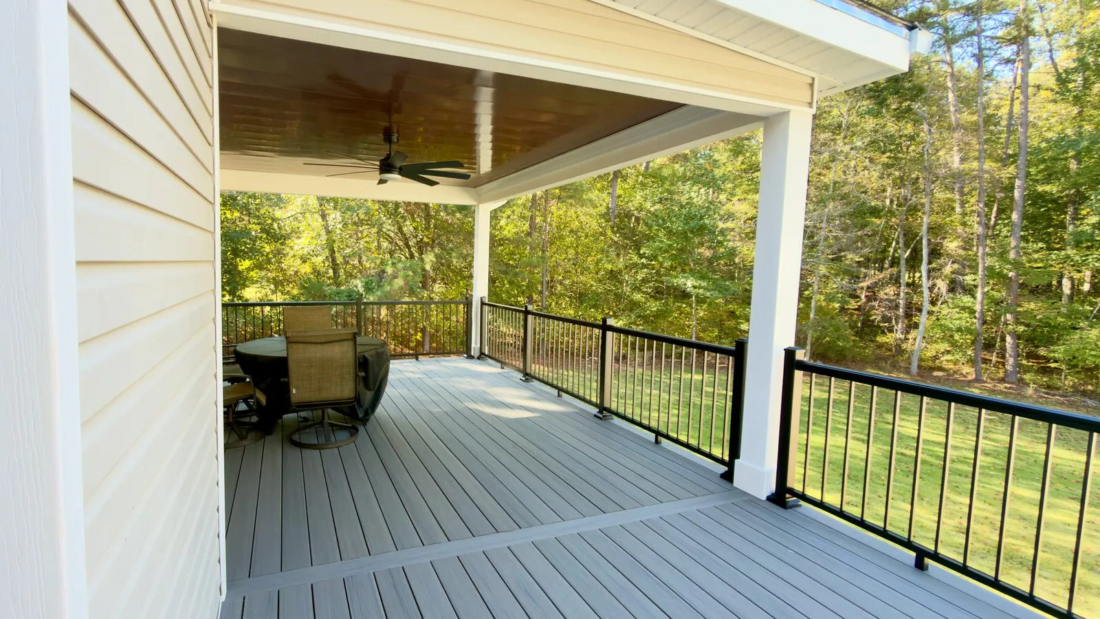 Under the roof: the copper-tone aluminum ceiling, a ceiling fan and an open view past the black rail