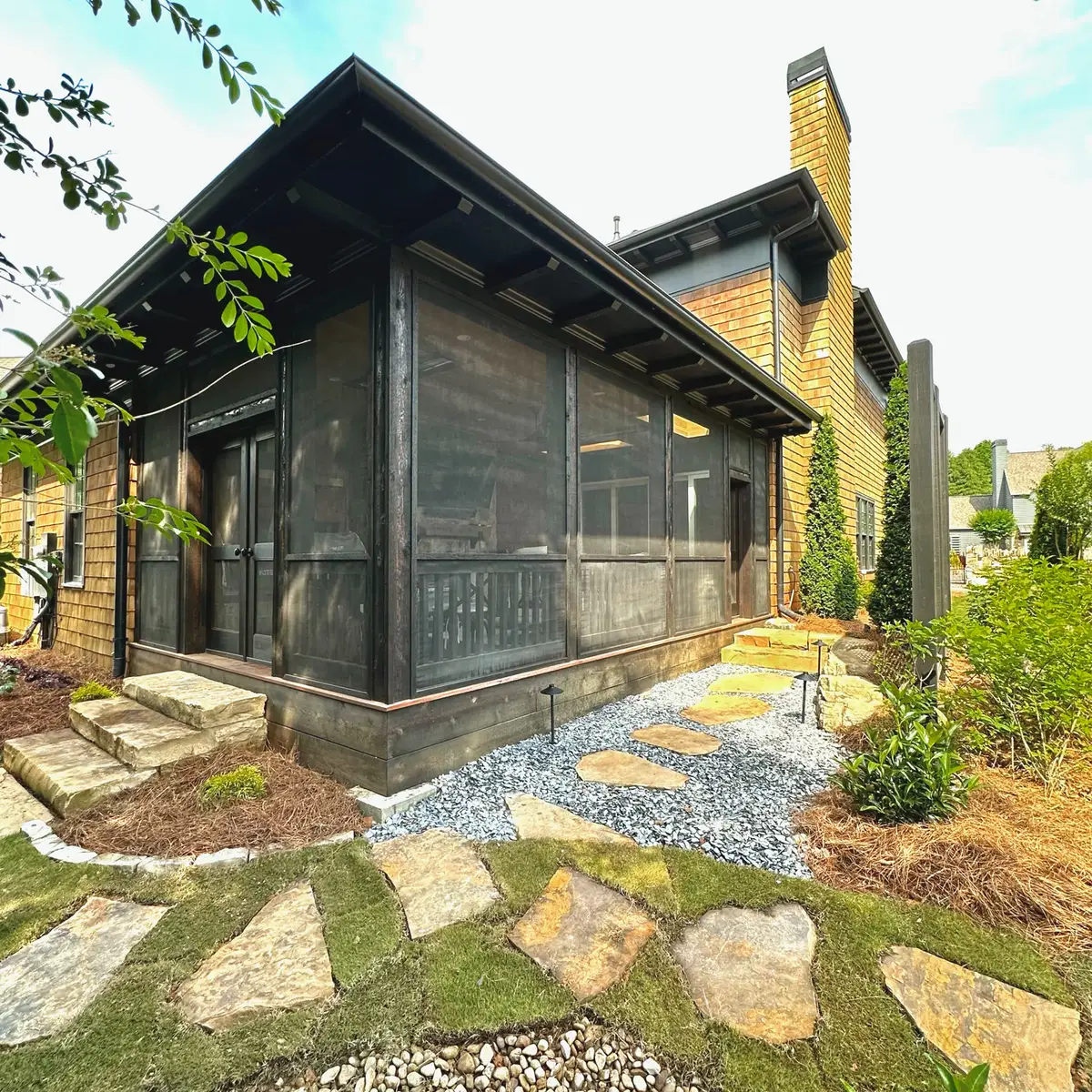 Black screened porch exterior with natural stone stepping path