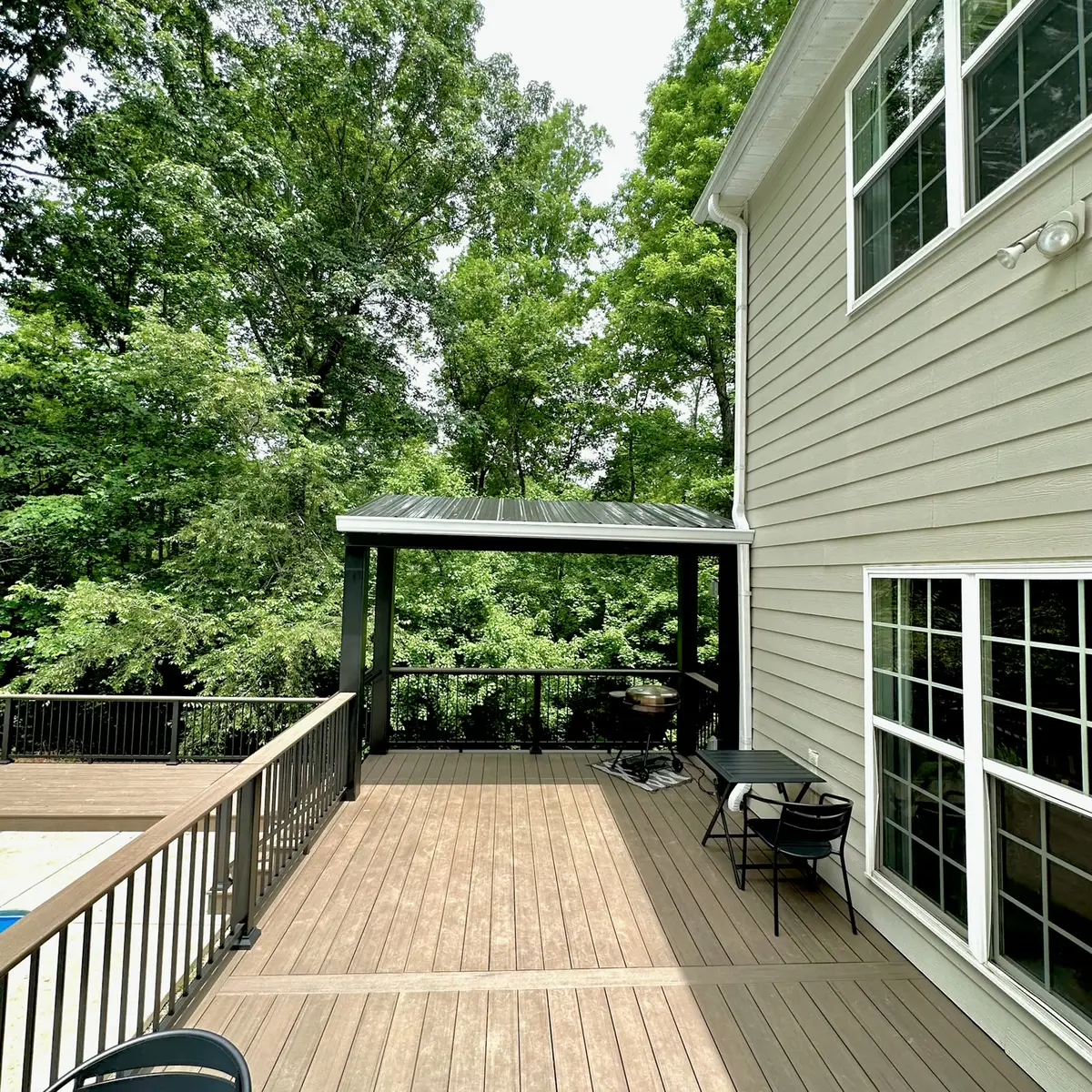 Composite deck with black railings and metal pergola beside a pool