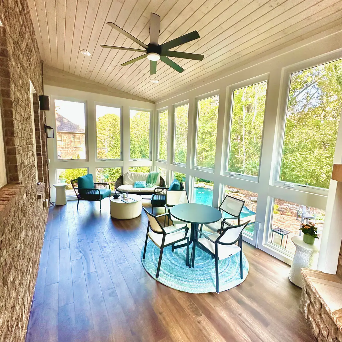 Sunroom with pine ceiling, ceiling fan and wall of windows overlooking a pool