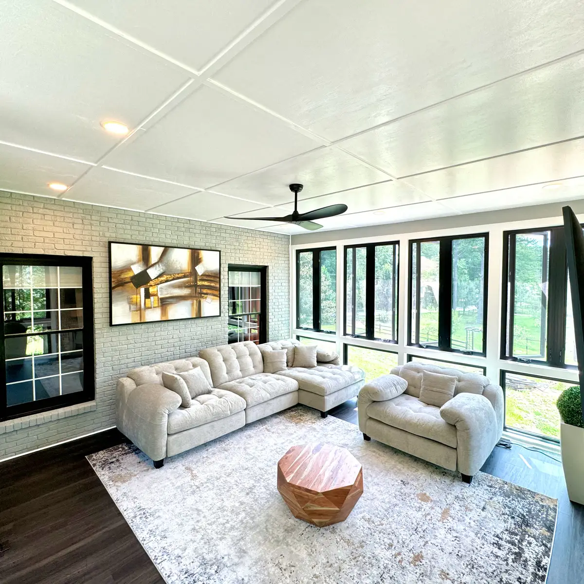 Bright sunroom with black-framed windows and lounge seating