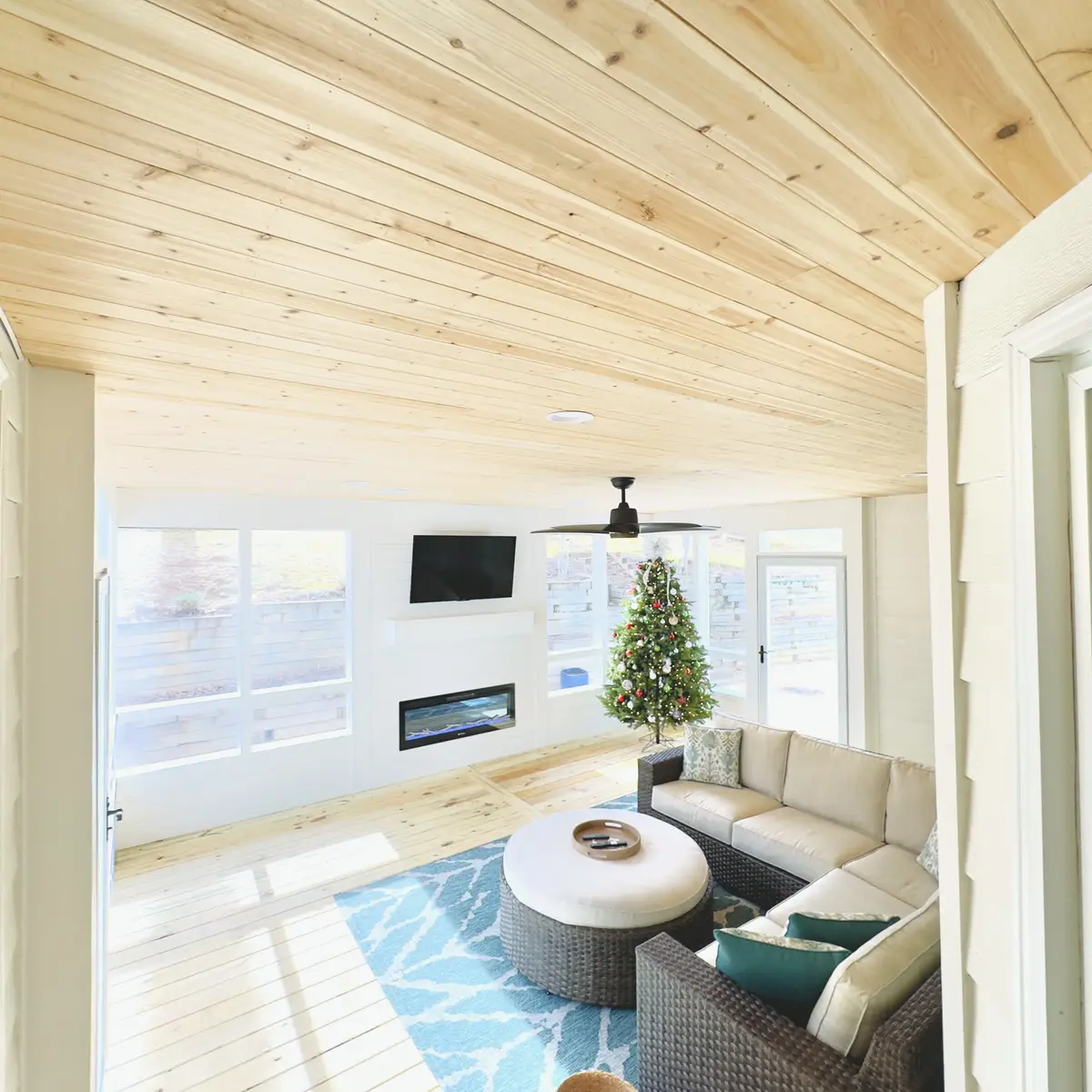 Pine-ceiling sunroom with sectional seating and fireplace