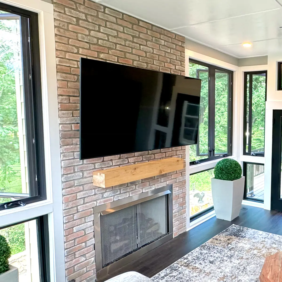 Brick fireplace with mounted TV in a sunroom addition